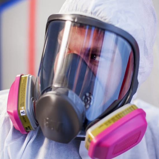 Mold Safe Solutions technician wearing a full-face respirator and protective suit inside a mold containment area